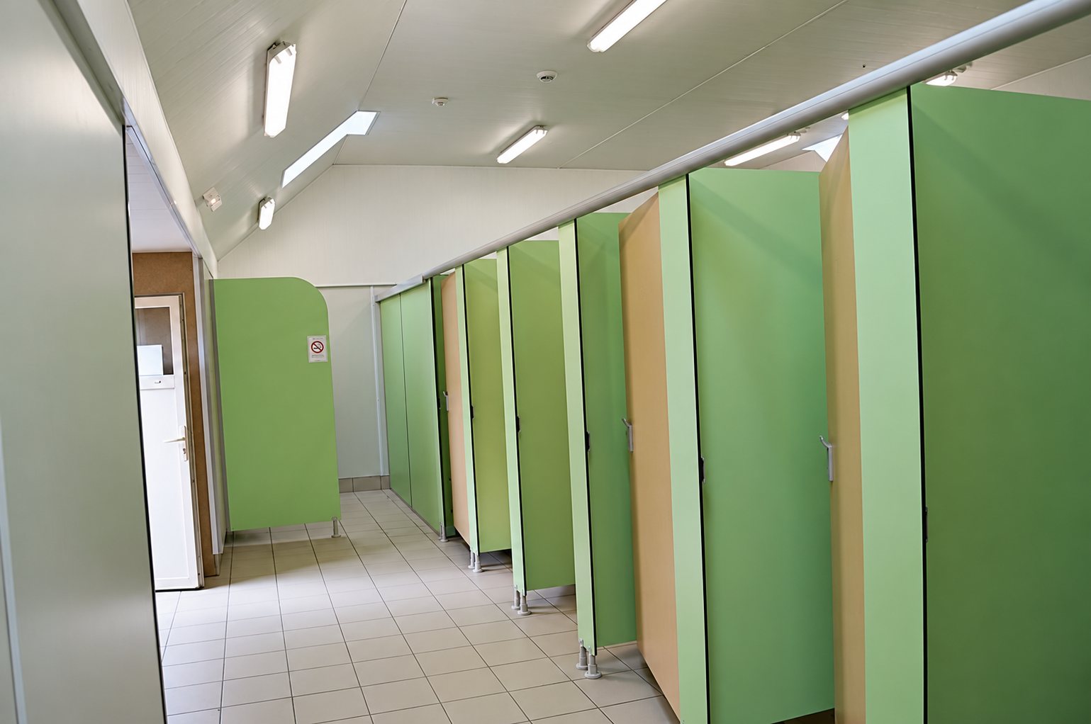 Cabines de toilettes vertes et beiges dans les sanitaires collectifs.