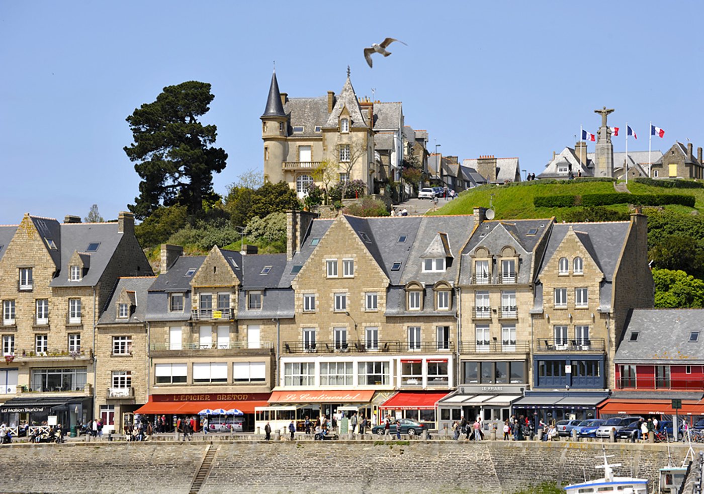 Façades en granit, commerces du port et château sur la colline.