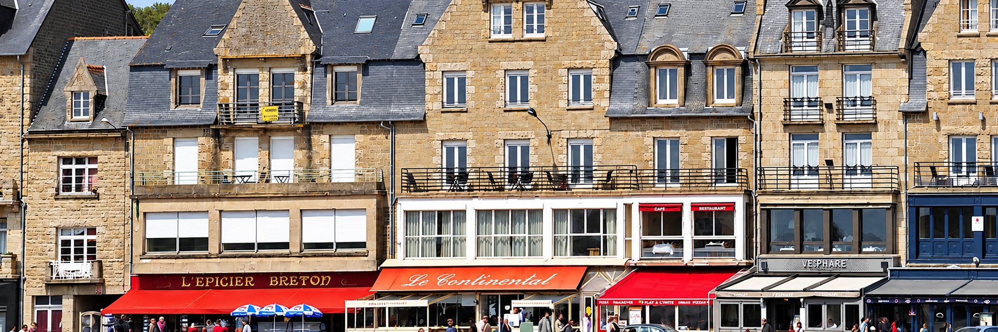 Façades en pierre, commerces et cafés sur le front de mer.