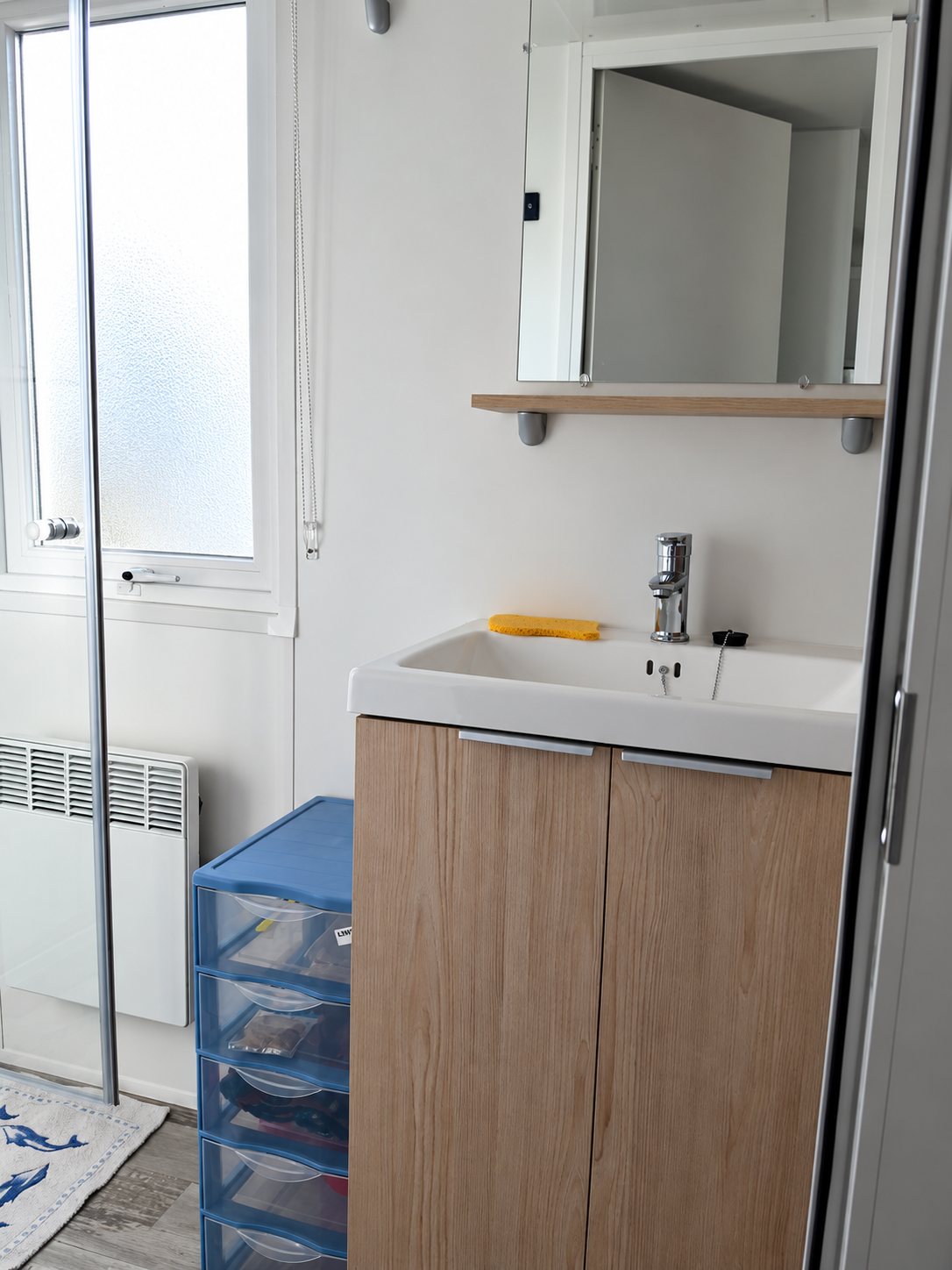 Petite salle de bain avec meuble vasque en bois et douche.