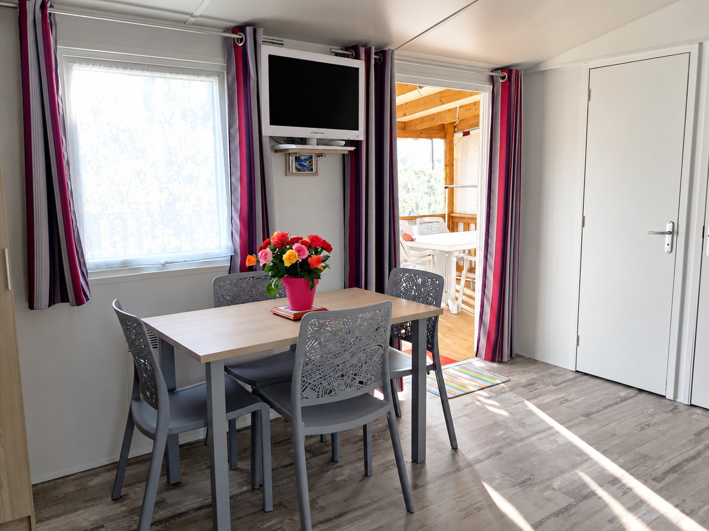 Salle à manger d’un mobil-home avec table et chaises roses.
