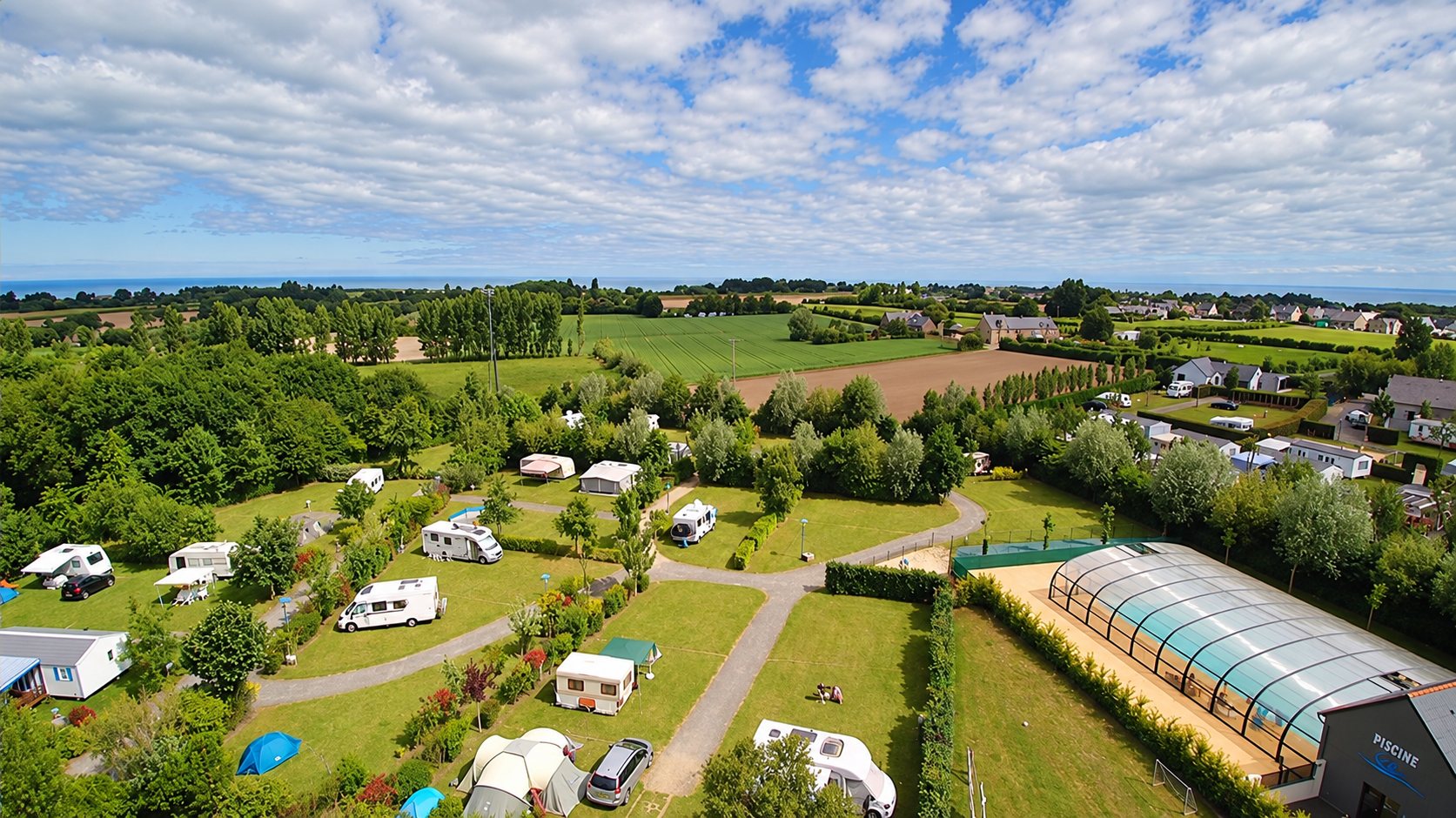 Vue aérienne du camping avec sa piscine couverte, non loin de la mer.